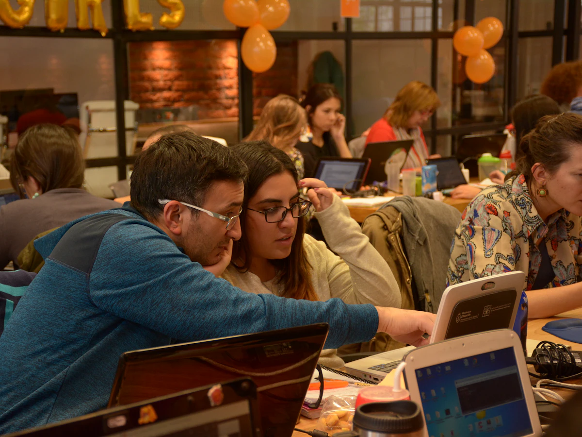 Learners working together on laptops at a community study session